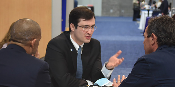 Marat Fudim engages in conversation with colleagues at a table.
