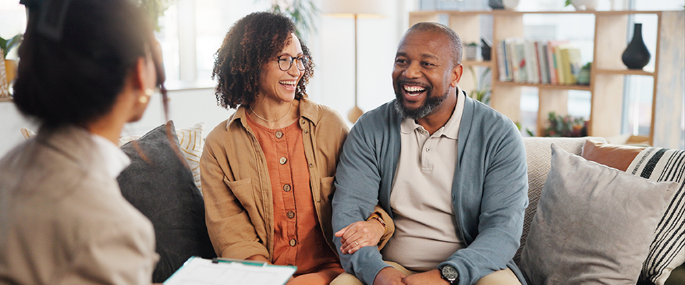 A smiling couple speak with a partner engagement specialist.