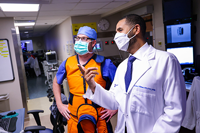 DCRI faculty member Kevin Thomas speaks with a colleague about a patient in the hospital. Both have face masks on.