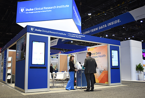 A wideshot of the DCRI exhibit booth at a recent conference. An operational expert stands at the entrance engaged in conversation with an attendee.