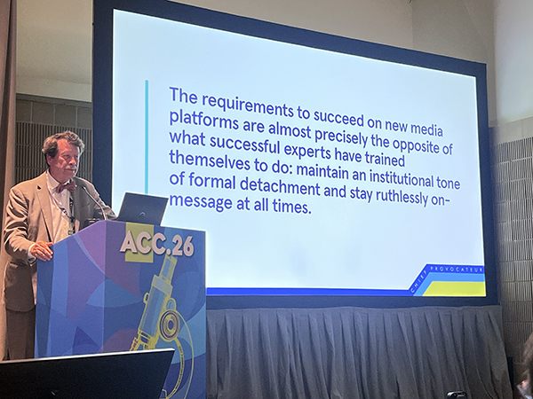 Rob Califf stands at a podium next to a slide that reads, "The requirements to succeed on new media platforms are almost precisely the opposite of what successful experts have trained themselves to do: maintain an institutional tone of formal detachment and stay ruthlessly on-message at all times."