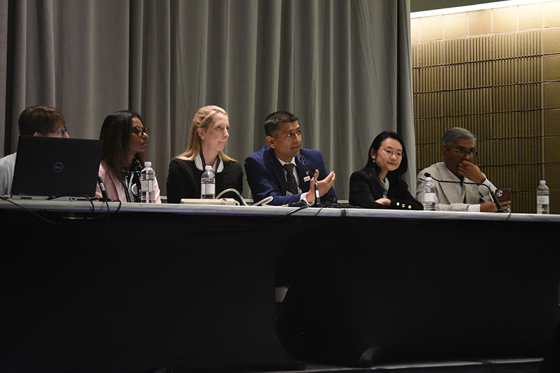 Nishant Shah sits on a panel of five people, in the middle, passionately discussing his research results.
