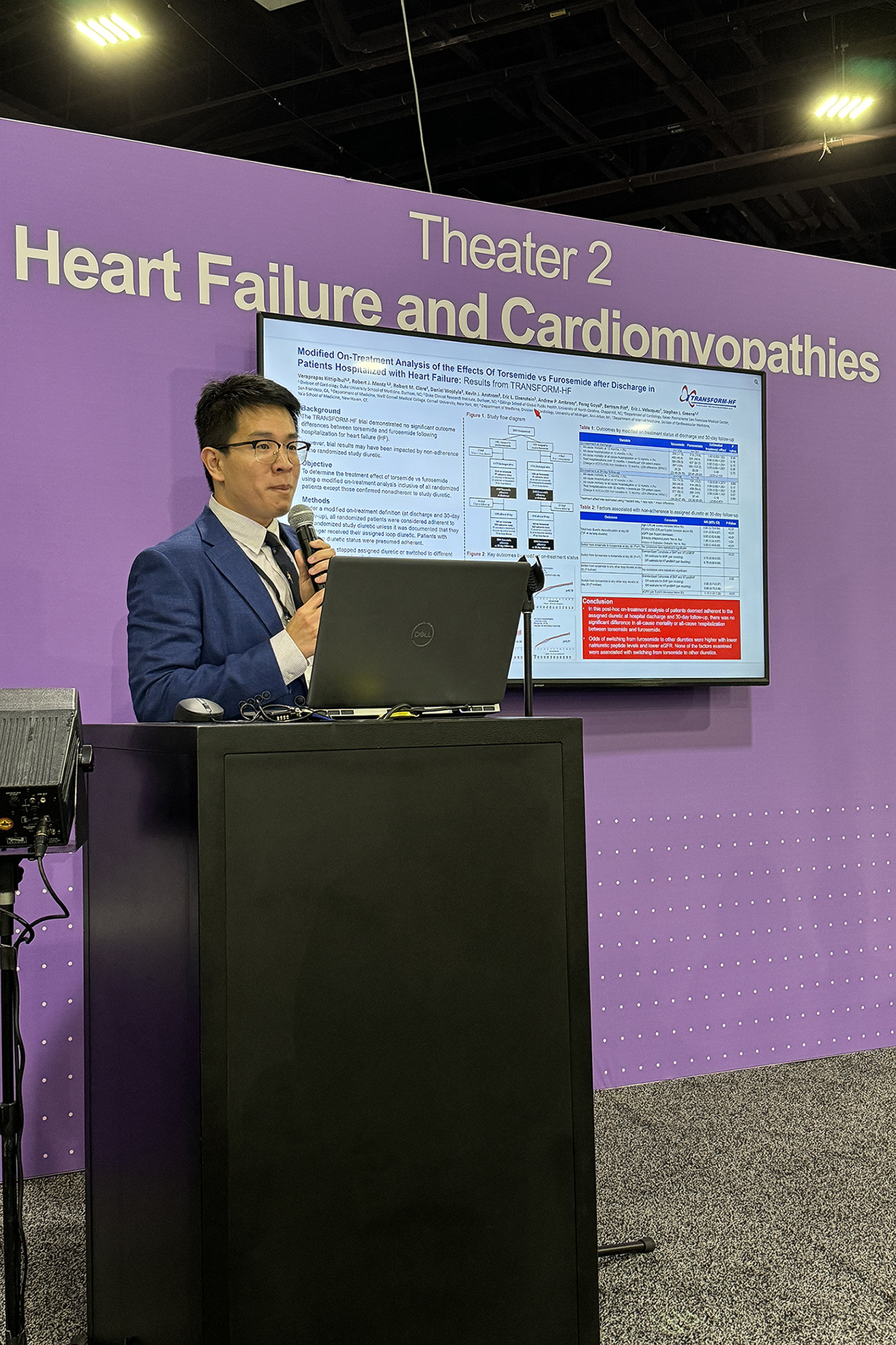 DCRI fellow Mark Kittipibul stands behind a podium with a digital poster showing on a screen behind him. 
